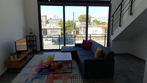 a living room with a blue couch and a large window at LOFT Ceremi in Marmara