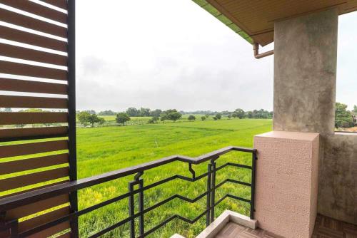 a balcony with a view of a green field at Nava Resort in Nakhon Nayok