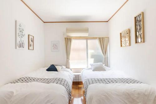 two twin beds in a room with a window at Abiko Stay in Osaka Namba in Osaka