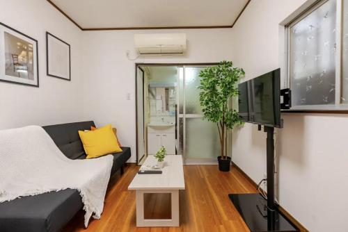a living room with a couch and a tv at Abiko Stay in Osaka Namba in Osaka