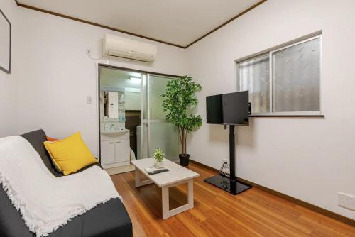 a living room with a couch and a tv at Abiko Stay in Osaka Namba in Osaka
