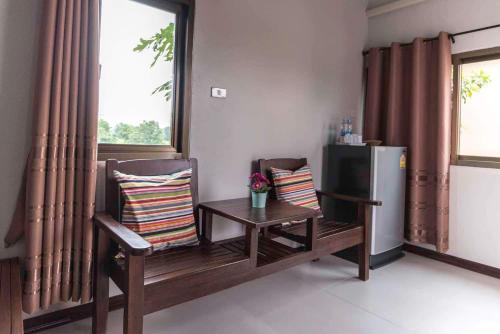 a room with a table and a chair and a refrigerator at Nava Resort in Nakhon Nayok