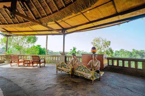 two men sitting on a couch on a patio at Bagus Jati Health & Wellbeing Retreat in Tegalalang