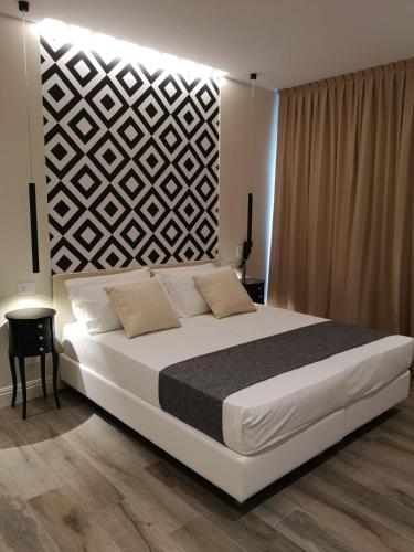 a bedroom with a large white bed and a wall at Luxmarì Hotel & Spa in Castellammare del Golfo