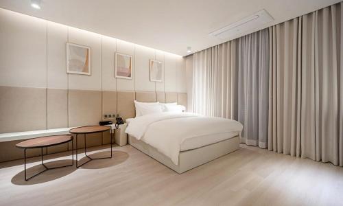 浦项Pohang Hotel Noblion的卧室配有白色的床和2张桌子