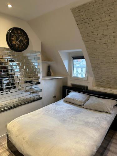 - une chambre avec un grand lit et une horloge murale dans l'établissement Studio avec vue sur Sacré-Coeur, à Paris