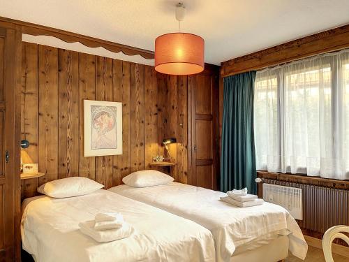 ヴェルビエにあるApartment Cimeblanche 7の木製パネルの壁の部屋にベッドが2つある