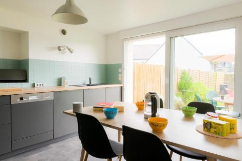 une cuisine avec une table et des chaises ainsi qu'une grande fenêtre dans l'établissement Maison pour 6 avec jardin - Centre de Névez, à Névez