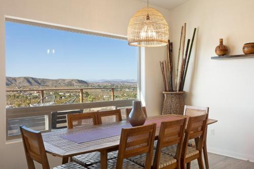 une salle à manger avec une table et des chaises et une grande fenêtre dans l'établissement Rancho Nopales JT - Pool, Hot Tub, Hammocks, Fast Wifi and Views! home, à Joshua Tree