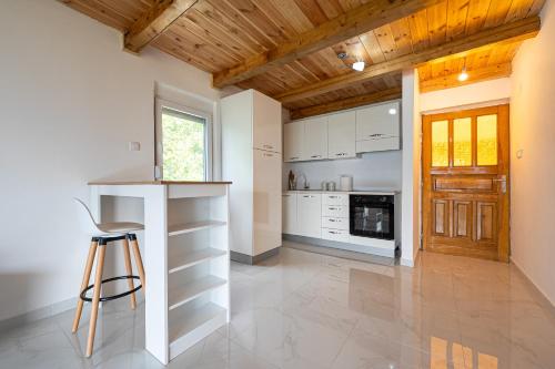 a kitchen with white cabinets and a wooden ceiling at Ostrog Retreat in Donja Povija