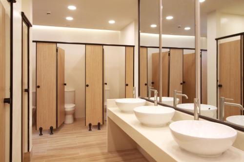 a bathroom with three sinks and two mirrors at Lub d Manila Makati - Central Makati, Near Nightlife in Manila