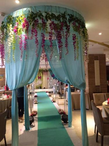 a long green aisle with blue curtains and flowers at Bestway Hotel Xi'an in Xi'an