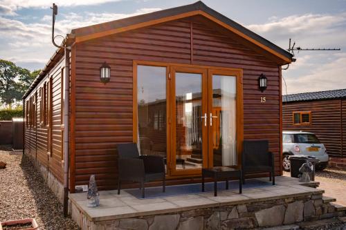 a wooden cabin with two chairs and a table at Luxury Lodge in Forfar