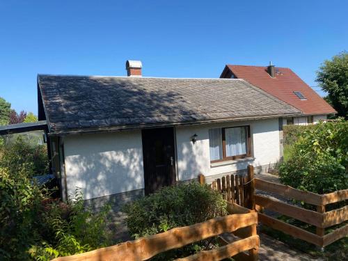a white house with a wooden fence in front of it at Ruhiger und renovierter Bungalow mit großem hundefreundlichem Garten zur Alleinnutzung in Remtengrün