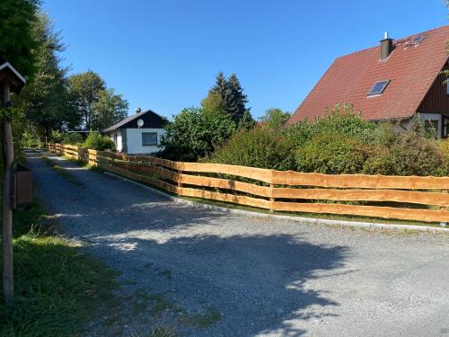 a wooden fence in front of a house at Ruhiger und renovierter Bungalow mit großem hundefreundlichem Garten zur Alleinnutzung in Remtengrün