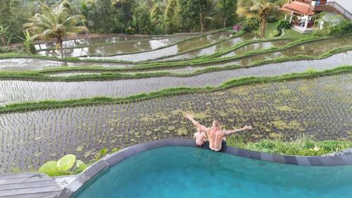 a man laying on the edge of a swimming pool at Lesong Hotel and Restaurant in Munduk