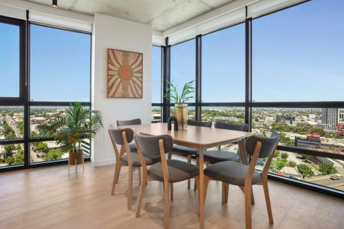 a dining room with a table and chairs and large windows at Deluxe Living in Southbank, Parking Available T&Cs in Melbourne