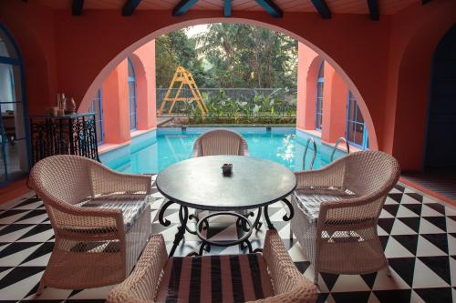 a patio with a table and chairs and a pool at Baia Luxe 3BHK Villa Pool & Jacuzzi, Mandrem Goa in Mandrem