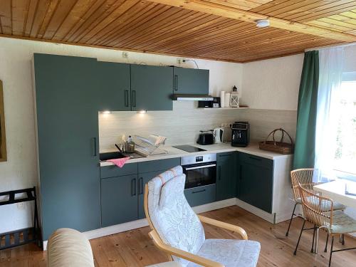 a kitchen with green cabinets and a table and chairs at Ruhiger und renovierter Bungalow mit großem hundefreundlichem Garten zur Alleinnutzung in Remtengrün
