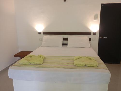 a white bed with two green towels on it at A Frame Cottage Udawalawe in Timbulketiya