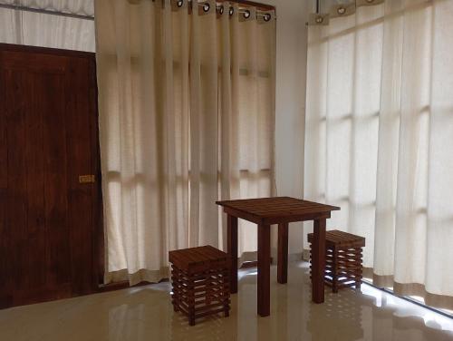 a wooden table and two stools in front of a window at A Frame Cottage Udawalawe in Timbulketiya