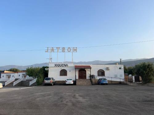 a building with cars parked in a parking lot at Pensión Xiquena in Fiñana