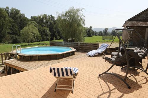 a patio with a swimming pool and two chairs at Gîte de la Rose in Saint-Vincent