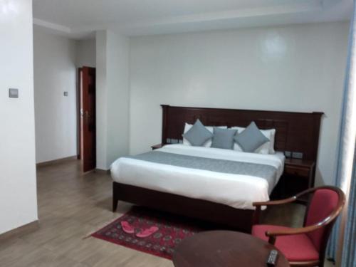 a bedroom with a large bed and a red chair at Twiga Whitehouse Villa in Nakuru