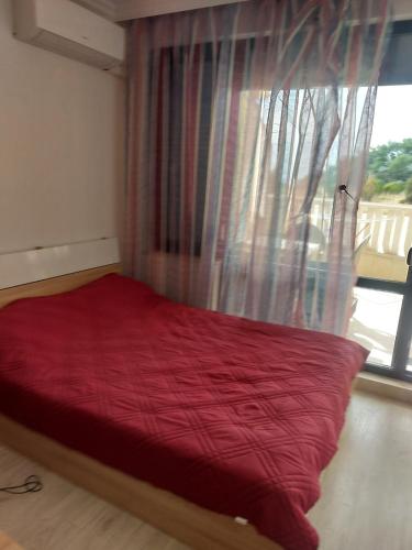 a red bed in a room with a window at Studio Sarafovo in Burgas