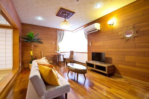 a living room with a couch and a tv at 安里戸建て in Tomari