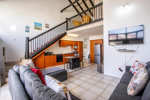 a living room with a couch and a staircase at Uvongo Cabanas 15A in Uvongo Beach