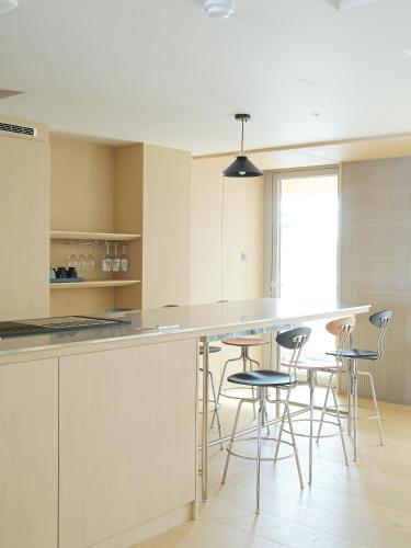 a kitchen with white cabinets and bar stools at B'amu Hotel in Busan