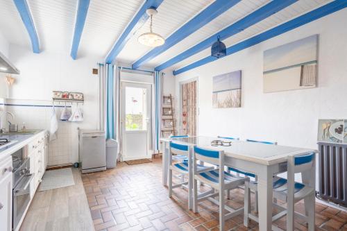 Il comprend une cuisine dotée de plafonds bleus, d'une table et de chaises. dans l'établissement Longère 5min de Pont-Aven, à Riec-sur-Bélon