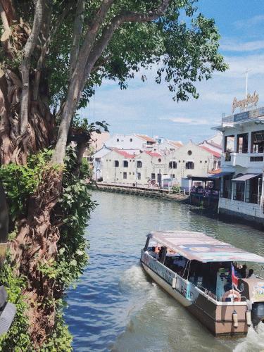 a boat traveling down a river with buildings at Cozy Home 3BR 8pax The Prive Malacca Jonker Street in Melaka