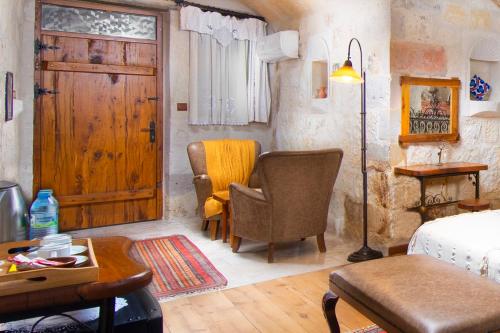 a bedroom with a bed and chairs and a door at Terra Cave Hotel in Goreme