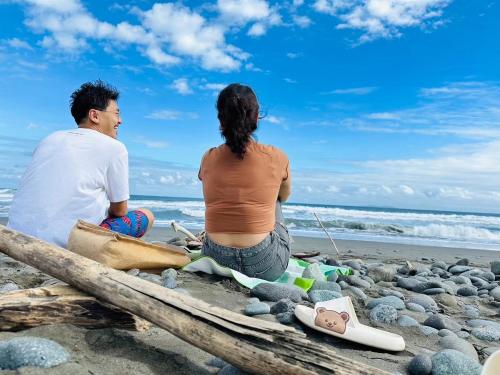 a man and a woman sitting on the beach at Dulan Tranquilo Hostel 台東都蘭晃輕鬆背包客棧 in Donghe