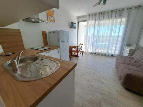 - une cuisine avec un évier au milieu d'un salon dans l'établissement Appartement rénové 2024, face à la mer, parking privé, terrasse, idéal famille! - FR-1-326-620, à Le Castellas