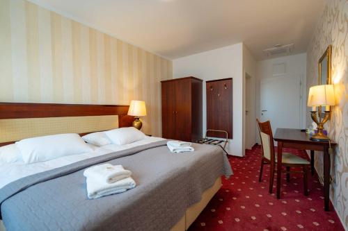 a hotel room with a bed with towels on it at Hotel Volf in Přeštice