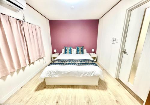 Un dormitorio con una cama con una pared morada. en 雨でも炭火BBQ可!プール付き!Max12名!駐車場2台!千畳敷三段壁近く, en Shirahama