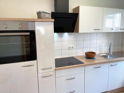 a kitchen with white cabinets and a black microwave at Ferienwohnung Frankenliebe in Bad Staffelstein