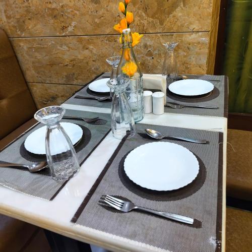 a table with white plates and utensils on it at Rich Grand Hotel in Agra