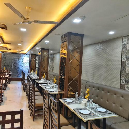 a dining room with tables and chairs in a restaurant at Rich Grand Hotel in Agra