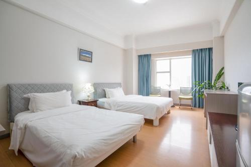 a hotel room with two beds and a window at Ha Luo Hotel in Kunming