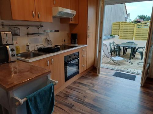 une cuisine avec des armoires en bois et un patio avec une table dans l'établissement Maison avec terrasse Merlimont Plage, à Merlimont
