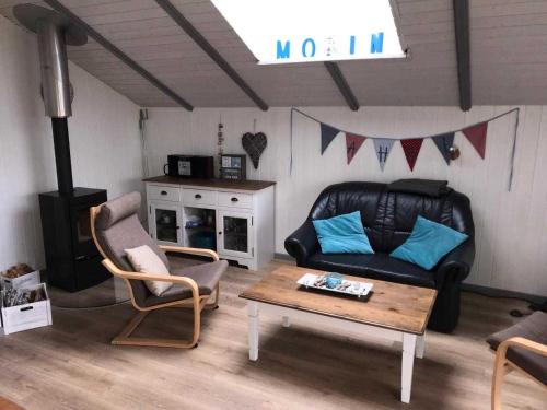 ein Wohnzimmer mit Sofa, Stühlen und einem Tisch in der Unterkunft Ferienhaus Küstenschwalbe in Schönhagen