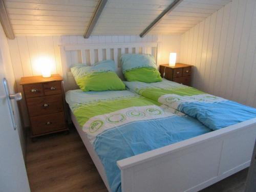 ein Bett mit blauer und grüner Bettwäsche und zwei Nachttischen in der Unterkunft Ferienhaus Küstenschwalbe in Schönhagen