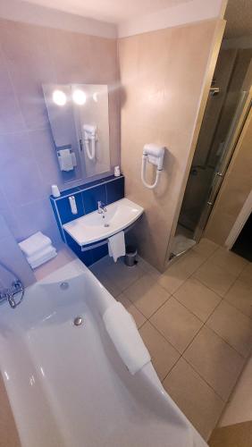 une salle de bain avec une baignoire et un lavabo dans l'établissement Enzo Hôtels Diane - Logis Amnéville, à Amnéville