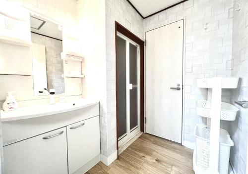 Un baño blanco con lavabo y espejo. en 雨でも炭火BBQ可!プール付き!Max12名!駐車場2台!千畳敷三段壁近く, en Shirahama