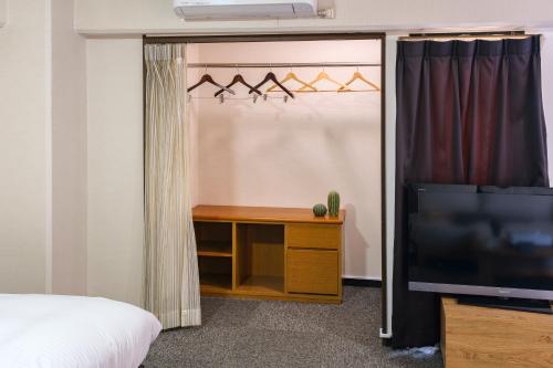 a room with a bed and a tv and a tv stand at Miyazaki Mango Hotel in Miyazaki