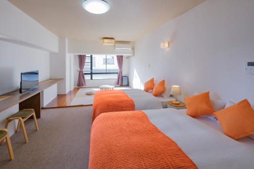 a hotel room with two beds and a television at Miyazaki Mango Hotel in Miyazaki